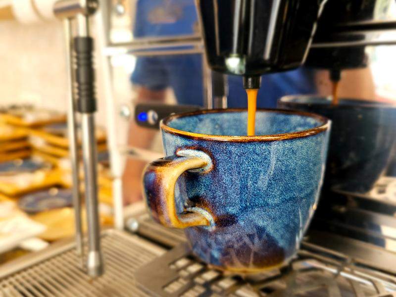 Koffie loopt uit de machine in een blauwe kop.