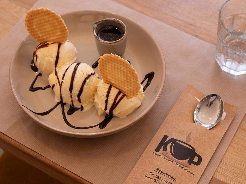 Een ijscoupe met chocoladesaus en wafeltjes.