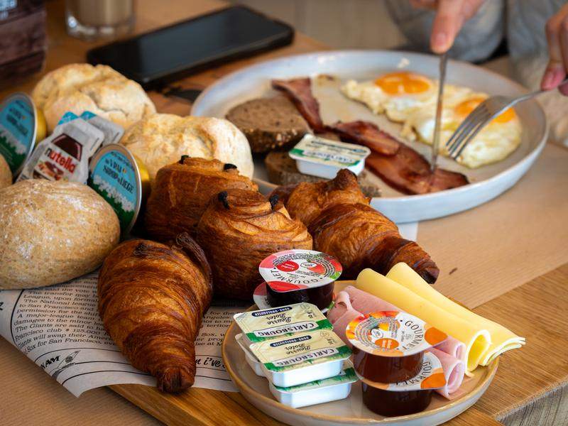 Een ontbijtplank vol broodjes, croissants, beleg en spiegeleieren.