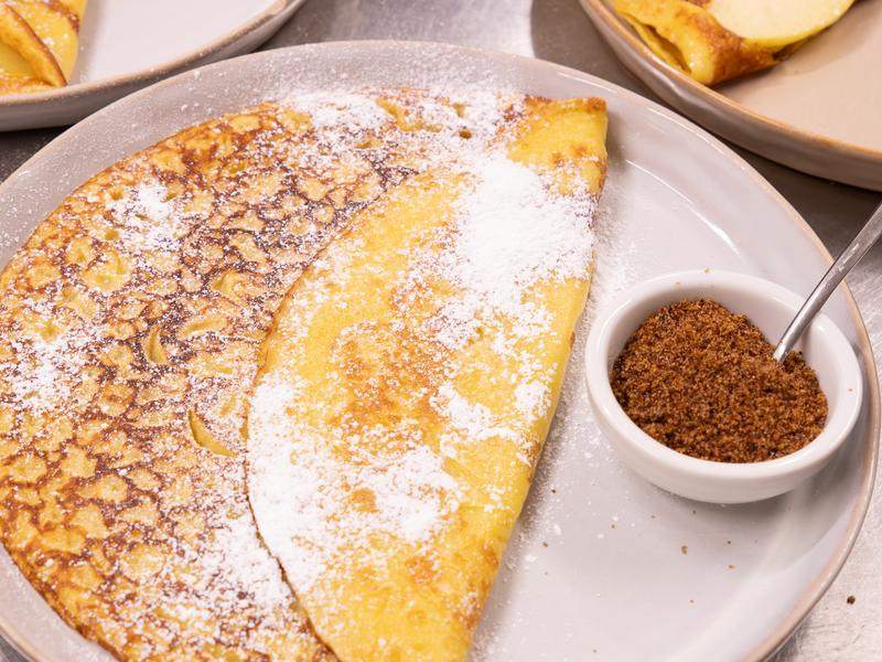 Pannenkoeken met poedersuiker en een potje bruine suiker.