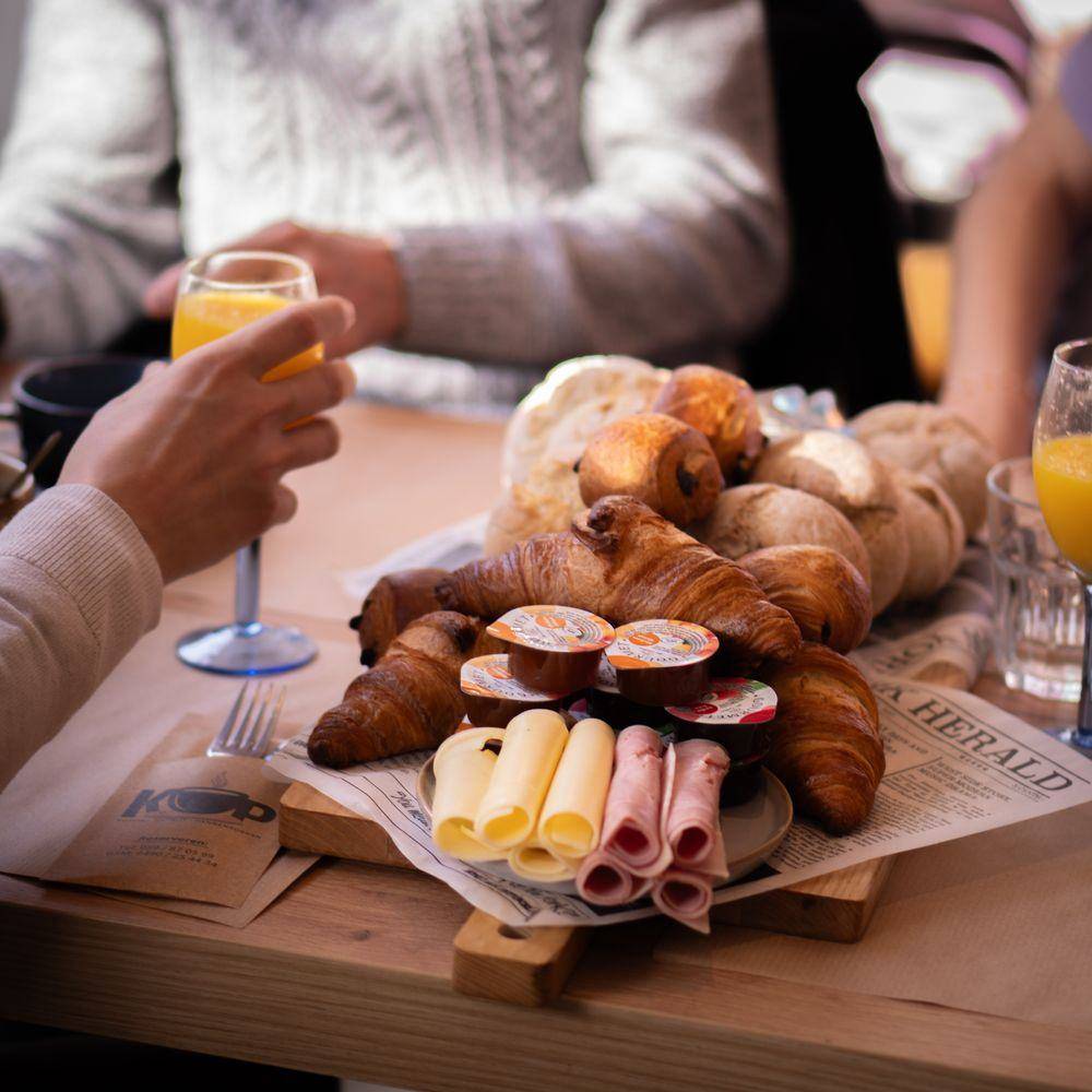 Een ontbijtplank met croissants, kaas en hesp, en een glas verse sinaasappelsap.